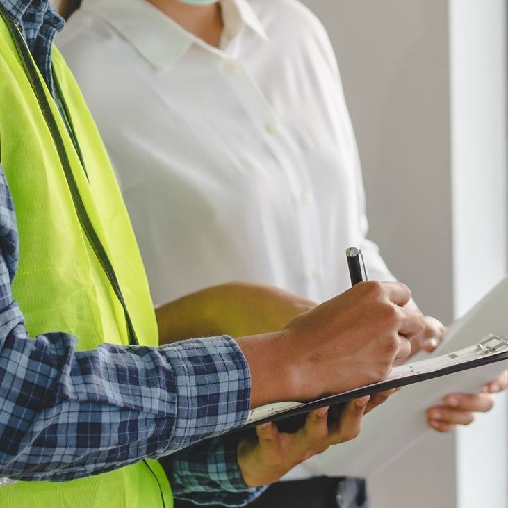 Un homme en gilet jaune écrit sur un presse-papiers tandis qu'une femme regarde.