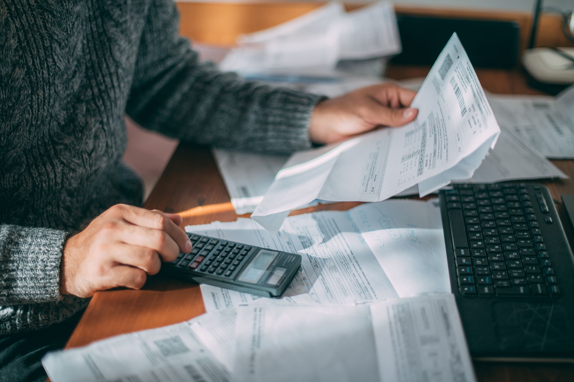 Un homme est assis à une table, utilise une calculatrice et regarde une facture.