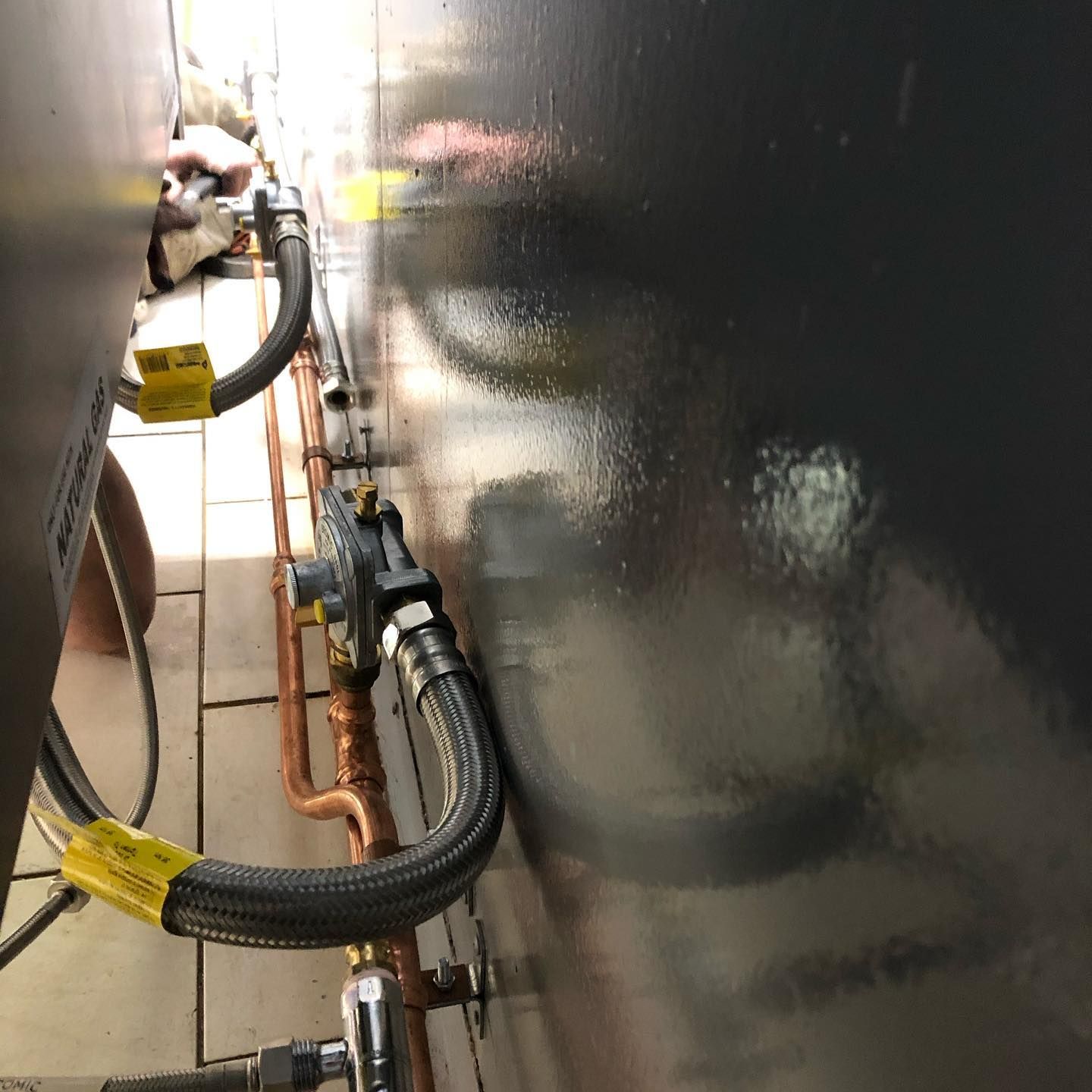 A Close Up Of A Hose Connected To A Gas Valve On A Wall — ARK Plumbing & Gasfitting In Exeter, NSW