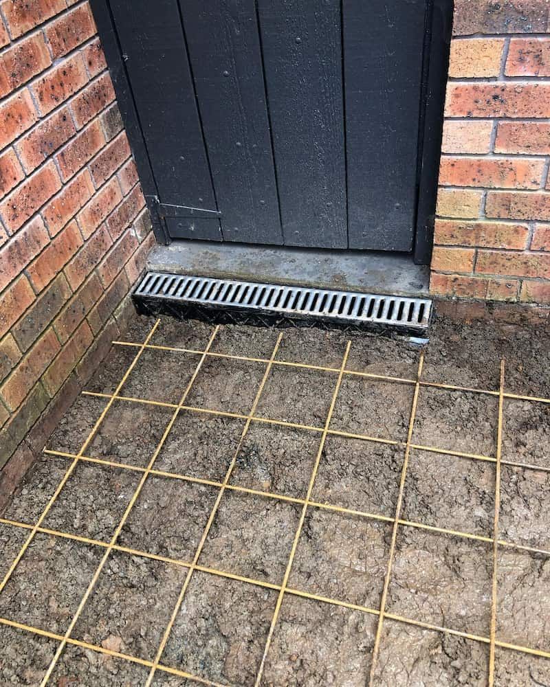 A Drain Is Sitting On The Ground Next To A Brick Wall — ARK Plumbing & Gasfitting In Moss Vale, NSW