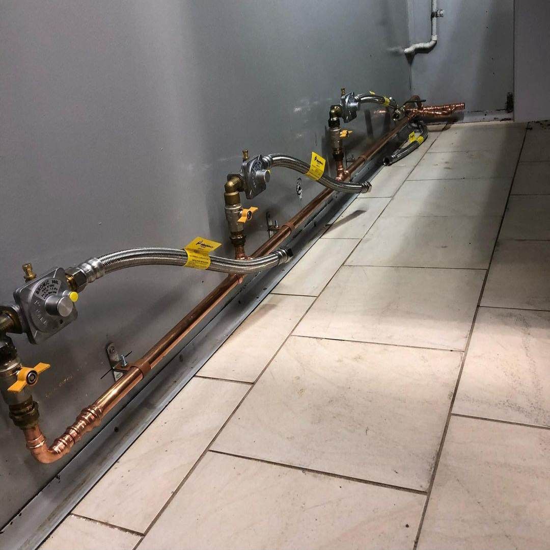 A Row Of Copper Pipes Are Lined Up Against A Wall — ARK Plumbing & Gasfitting In Mittagong, NSW
