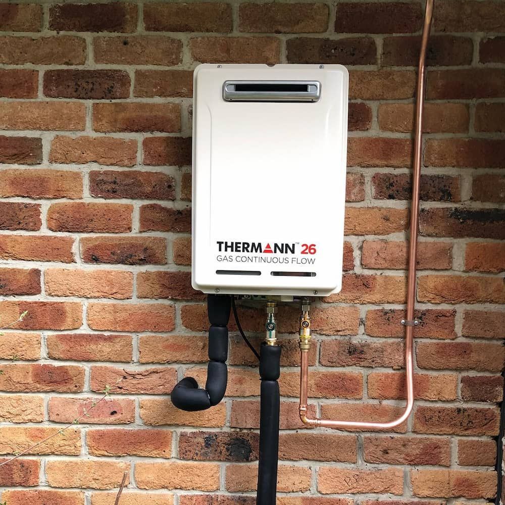 A White Water Heater Is Attached To A Brick Wall — ARK Plumbing & Gasfitting In Mittagong, NSW