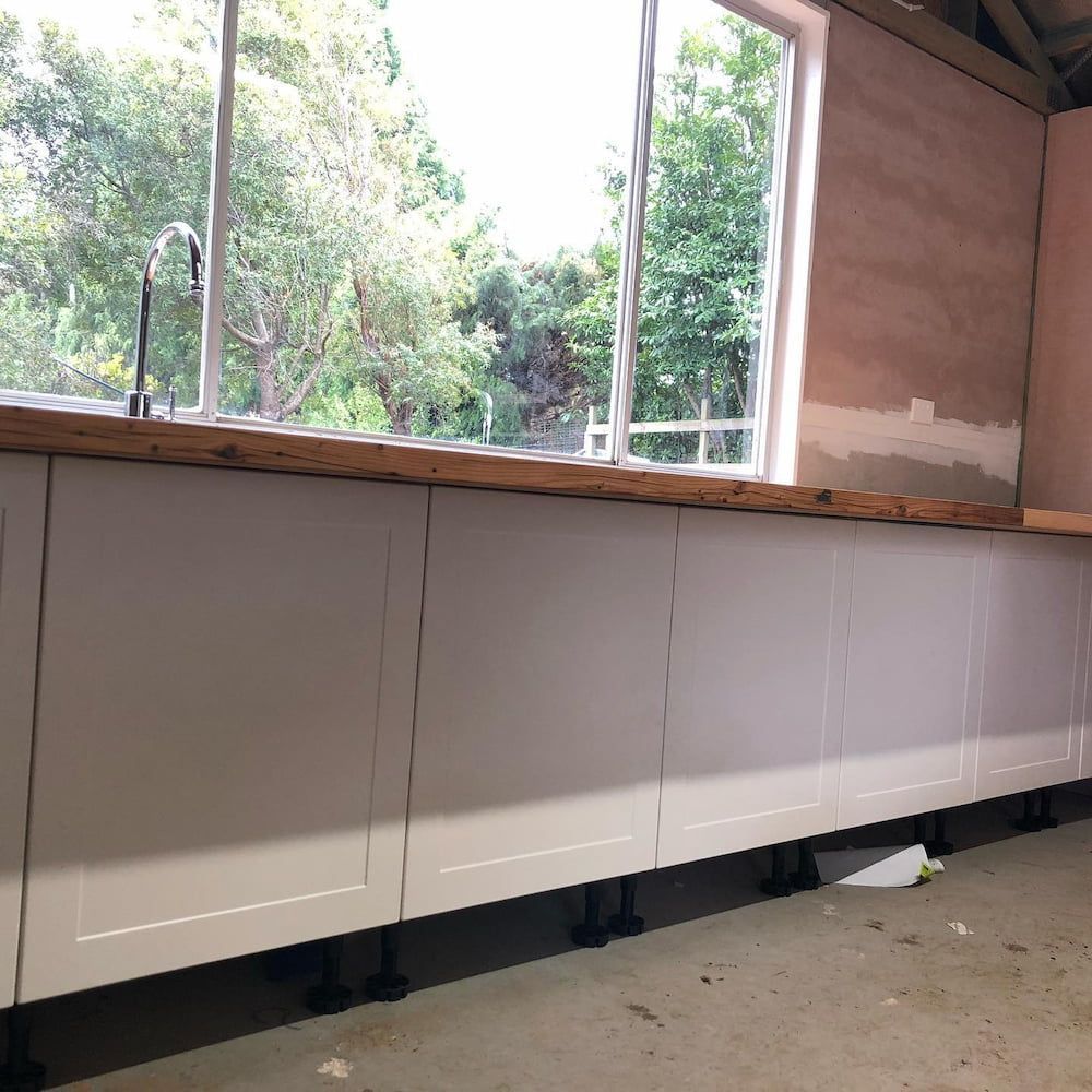 A Kitchen With White Cabinets And A Large Window — ARK Plumbing & Gasfitting In Exeter, NSW