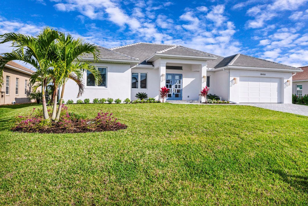 A white house with a lush green lawn in front of it.