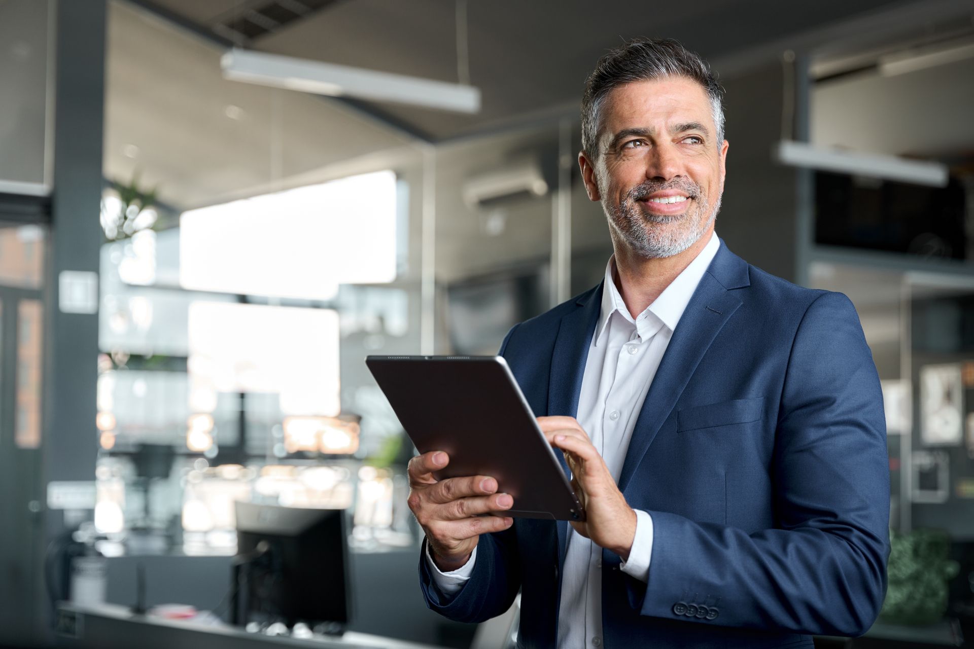 a man in a suit is holding a tablet in an office .