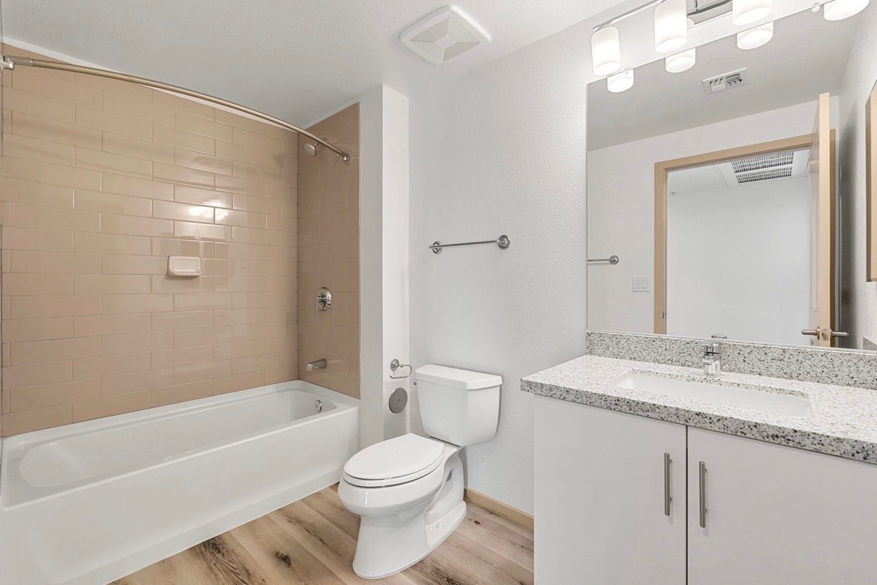 Bathroom in an apartment with a tub/shower, toilet, and granite vanity.