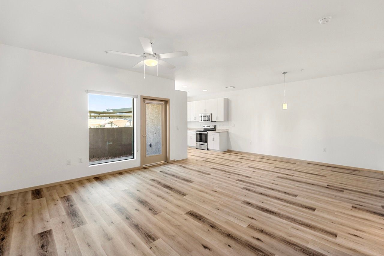 Open living area with laminate floors, ceiling fan, and a door to the outdoors.