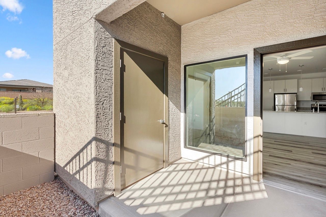 Front entry door next to a large window; interior shows a modern kitchen.