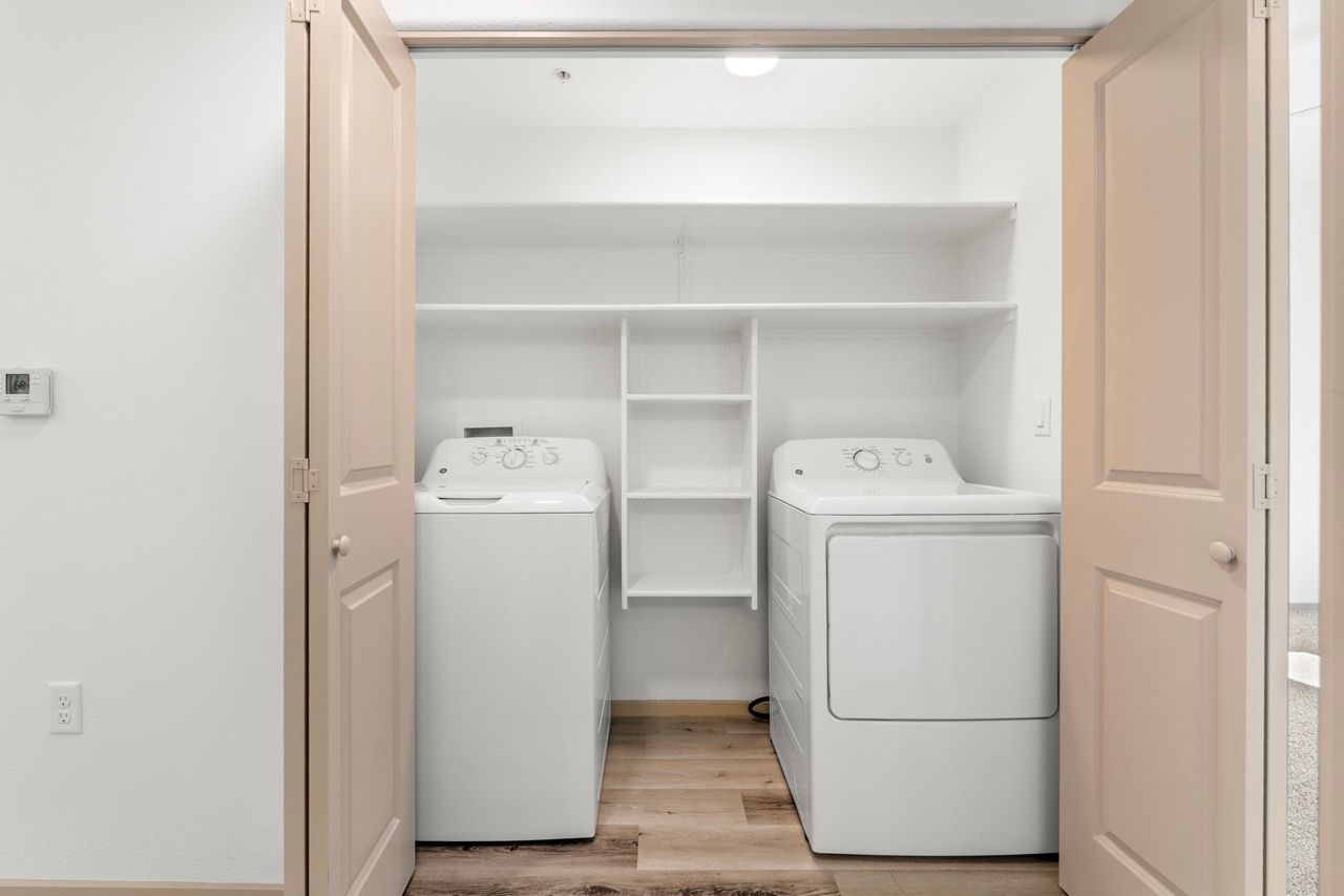 Laundry closet with side-by-side washer and dryer and built-in shelves.