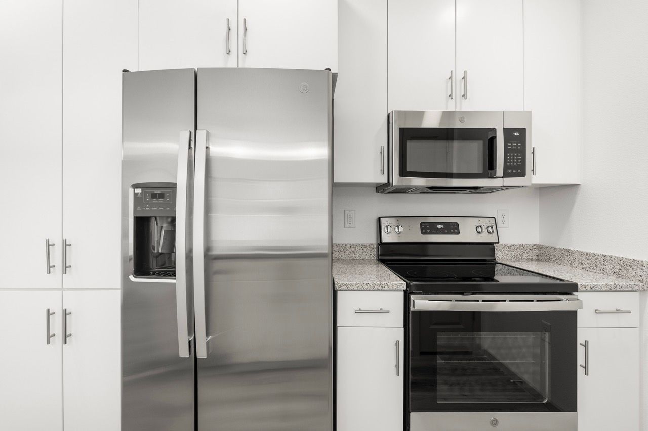 Modern apartment kitchen with stainless steel refrigerator, microwave, and stove.