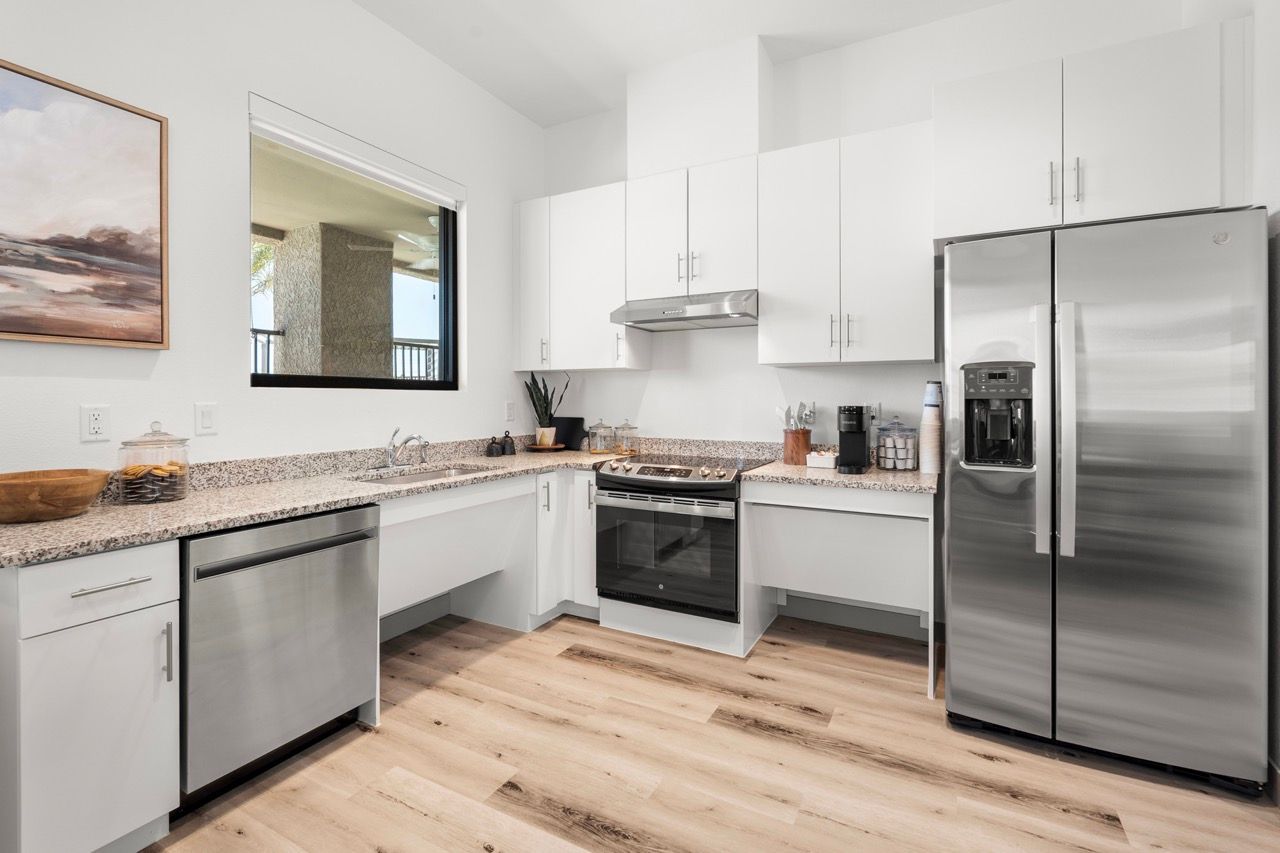 White kitchen with granite countertops, stainless steel refrigerator, stove, and dishwasher.