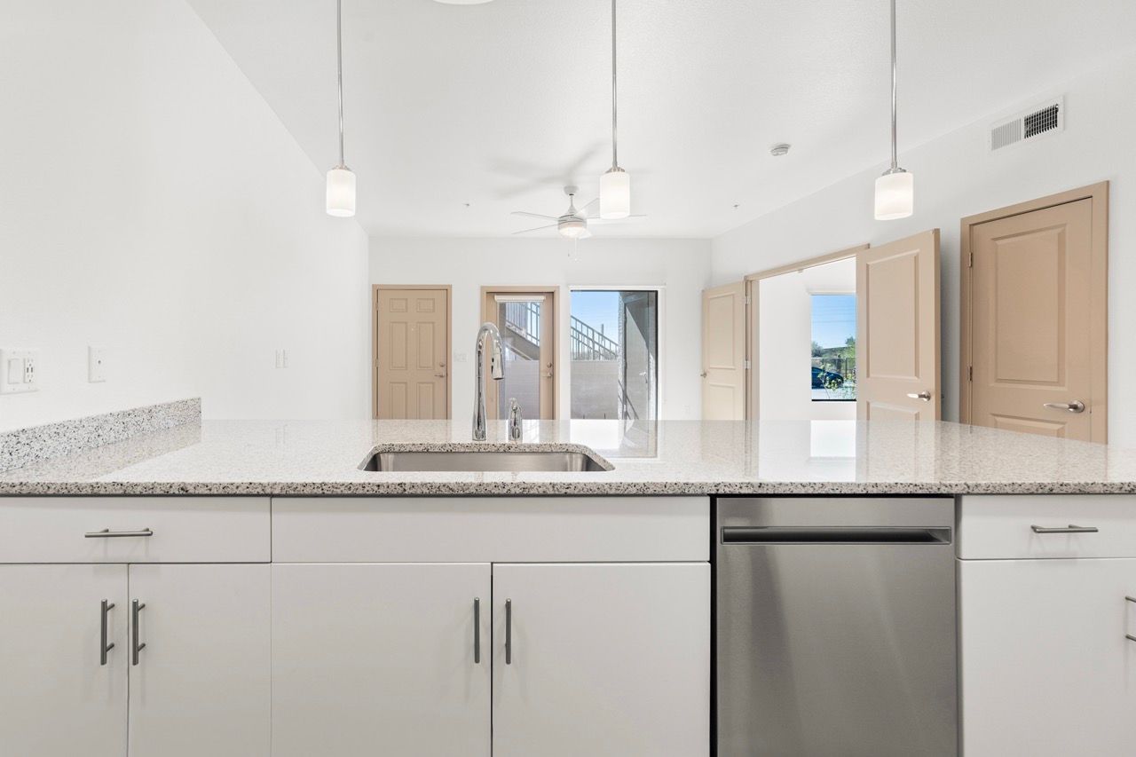 Open kitchen with granite countertops, sink, and stainless steel dishwasher.