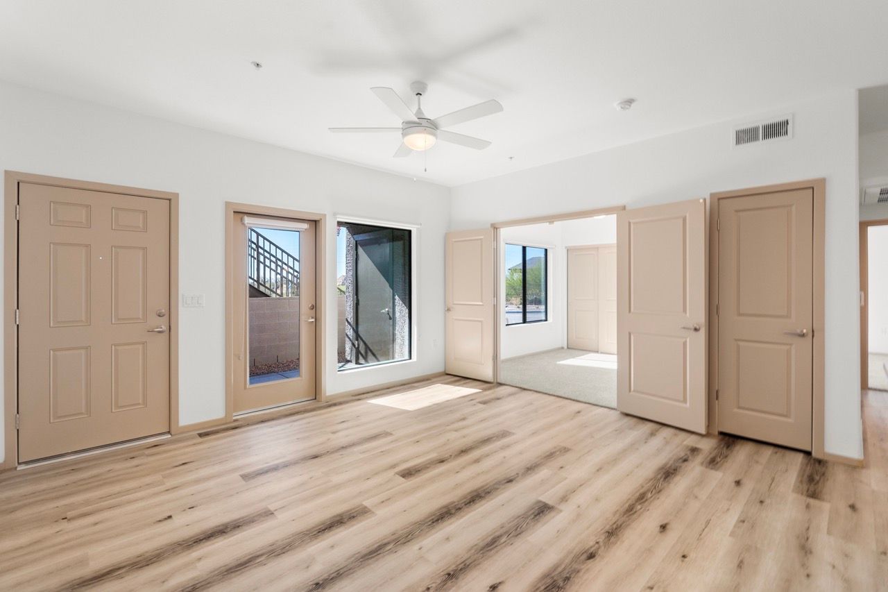 Interior living area with light wood flooring, beige doors, and large windows.
