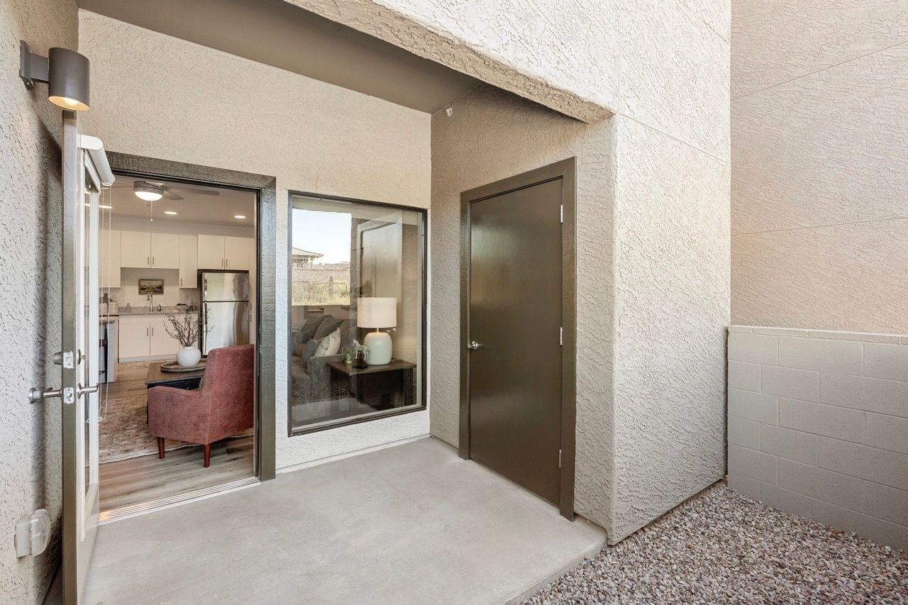 Ground-level apartment entry with glass doors; living room and kitchen visible inside.