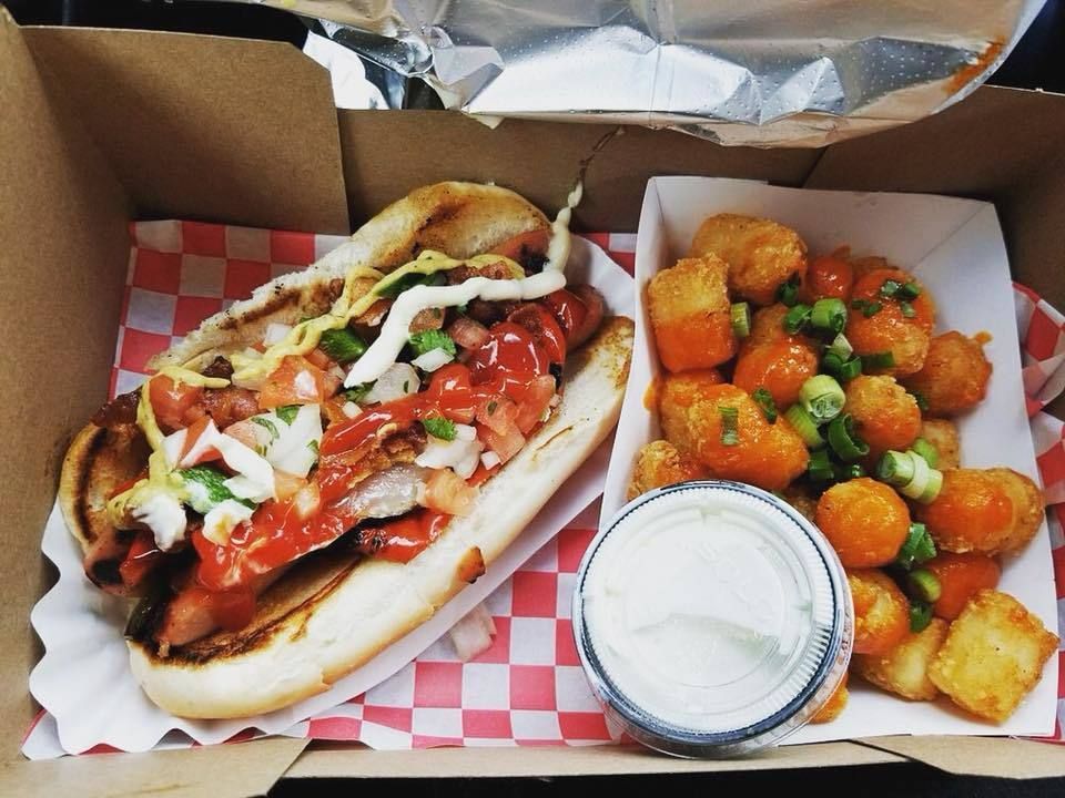 A box of food with a hot dog and potato tots