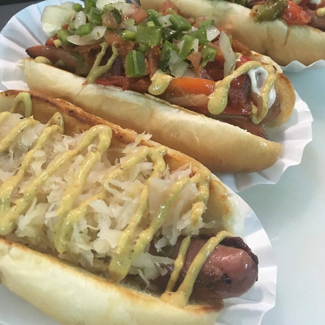 Three hot dogs are lined up on a paper plate