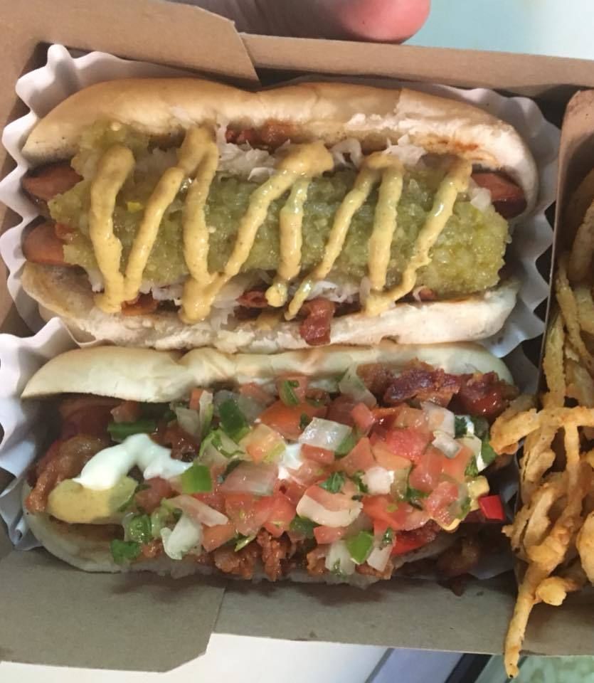 A person is holding a box of hot dogs and french fries