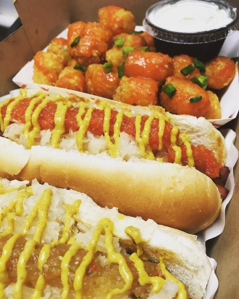 A box of hot dogs with mustard and buffalo tots