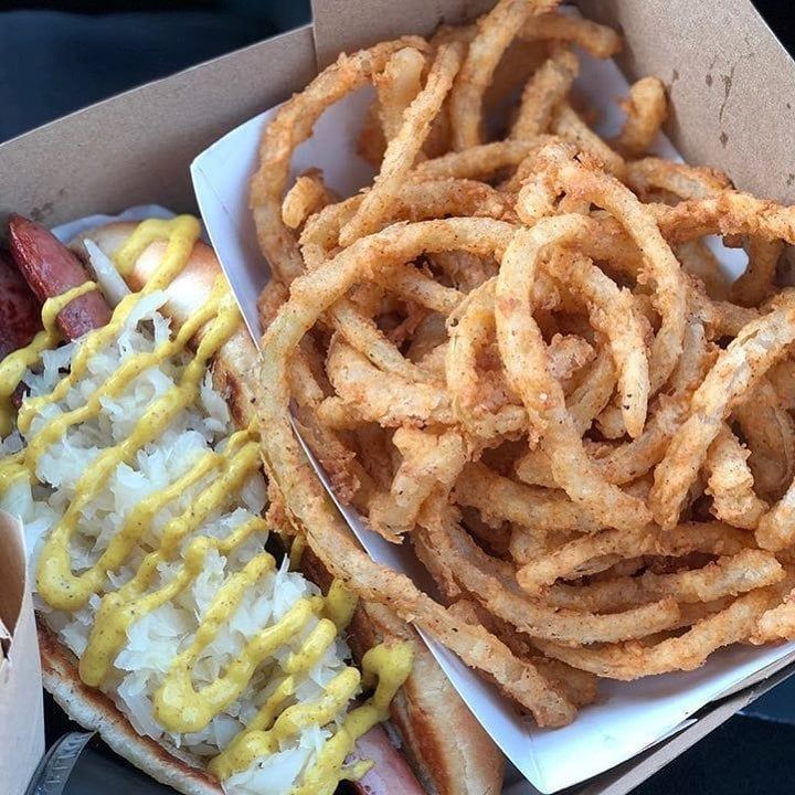 A hot dog and onion rings in a cardboard box