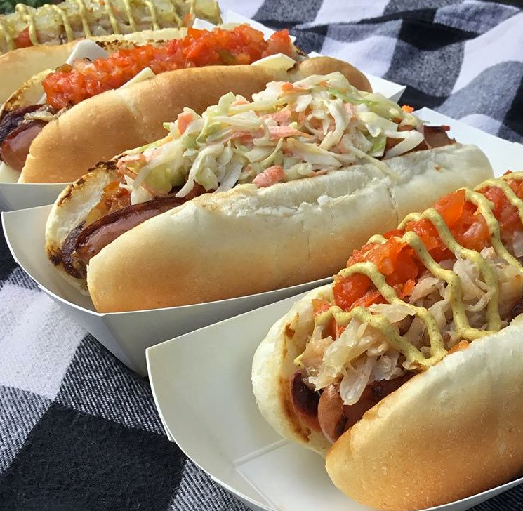 A bunch of hot dogs with different toppings on them
