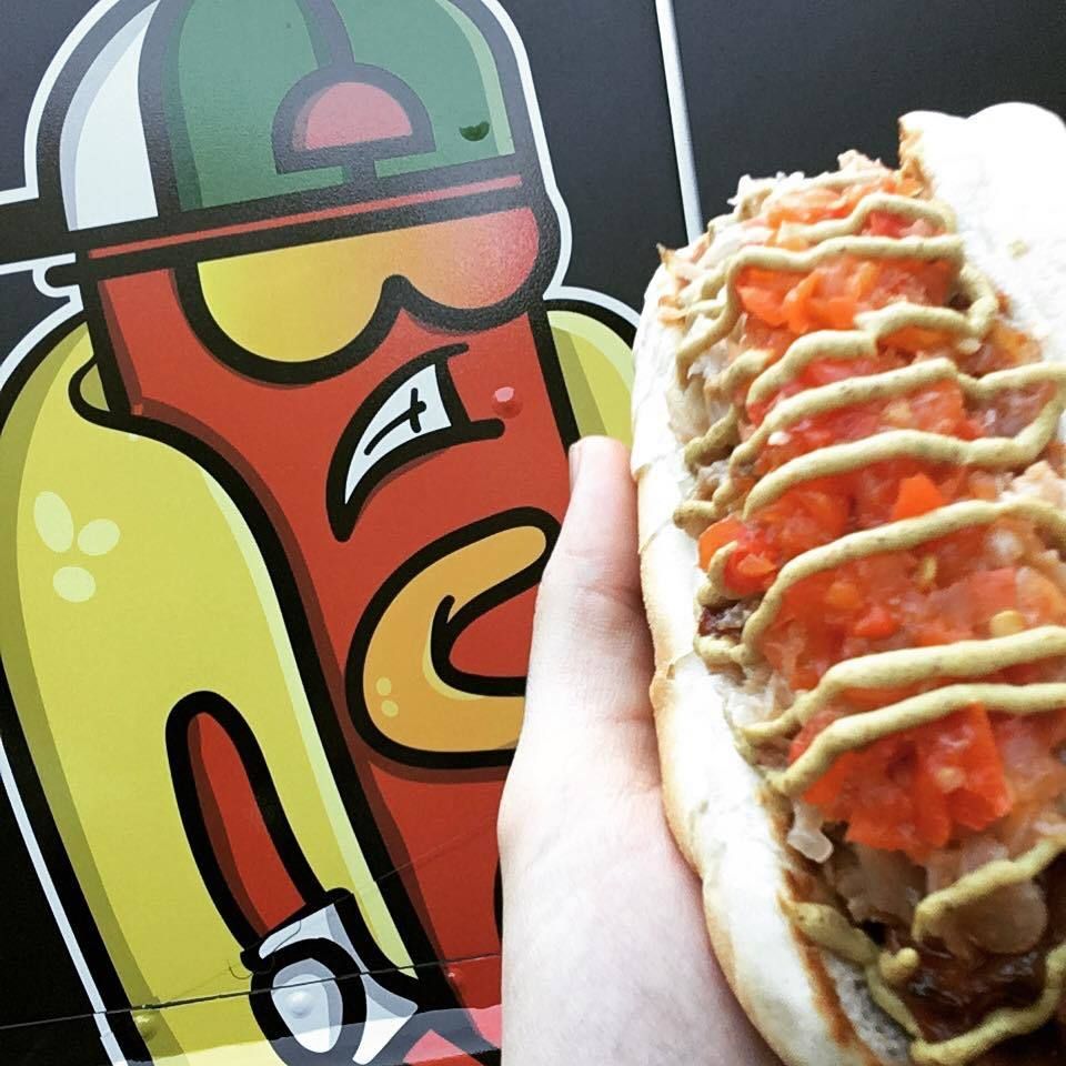 A person is holding a hot dog with mustard and tomatoes