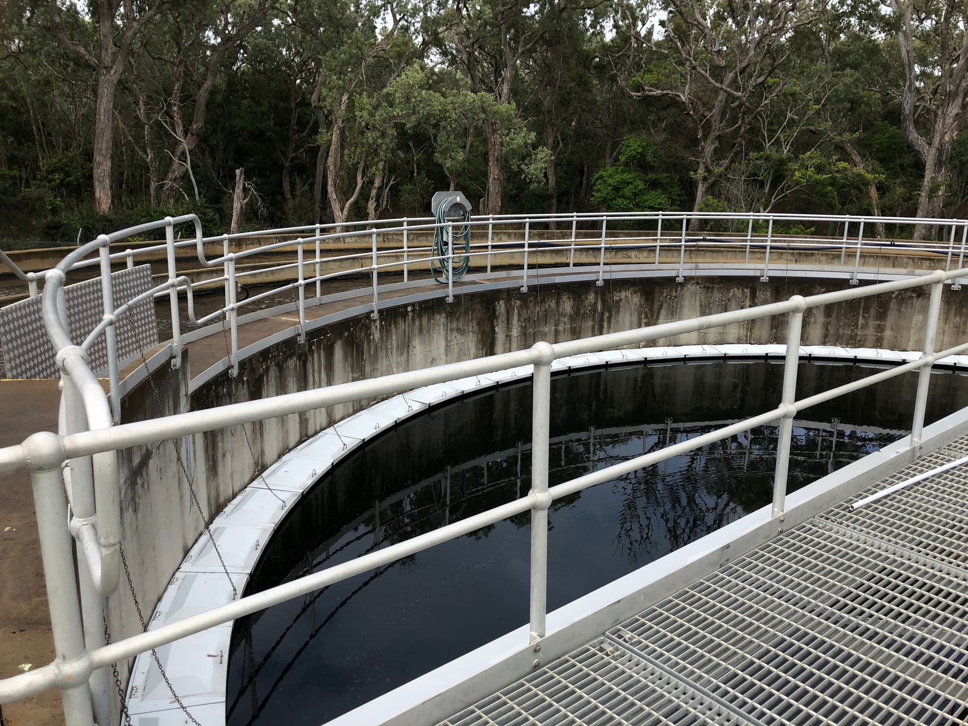 There is a fence around a large tank of water.
