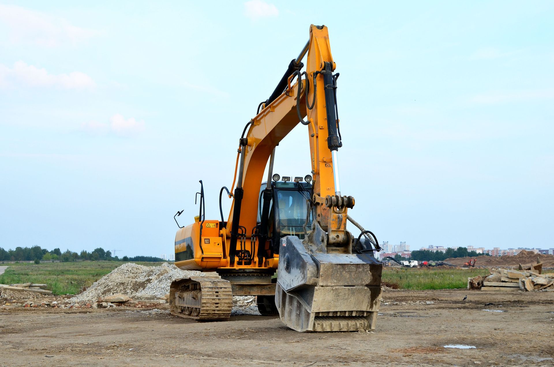 A yellow excavator is parked in a dirt field.