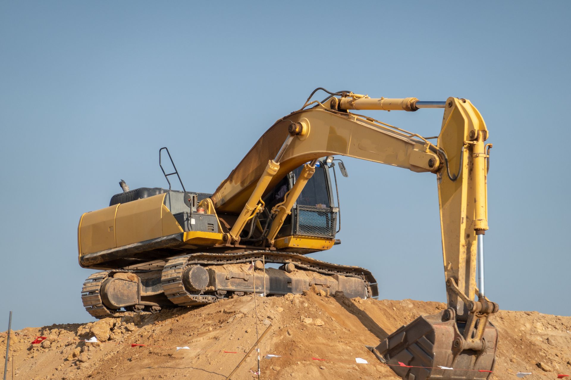A yellow excavator is sitting on top of a pile of dirt.