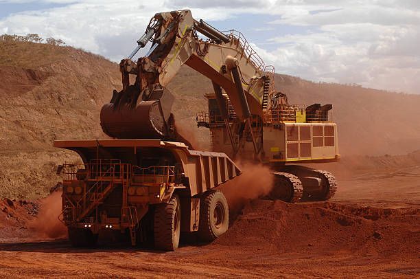 A large excavator is loading a dump truck with dirt.