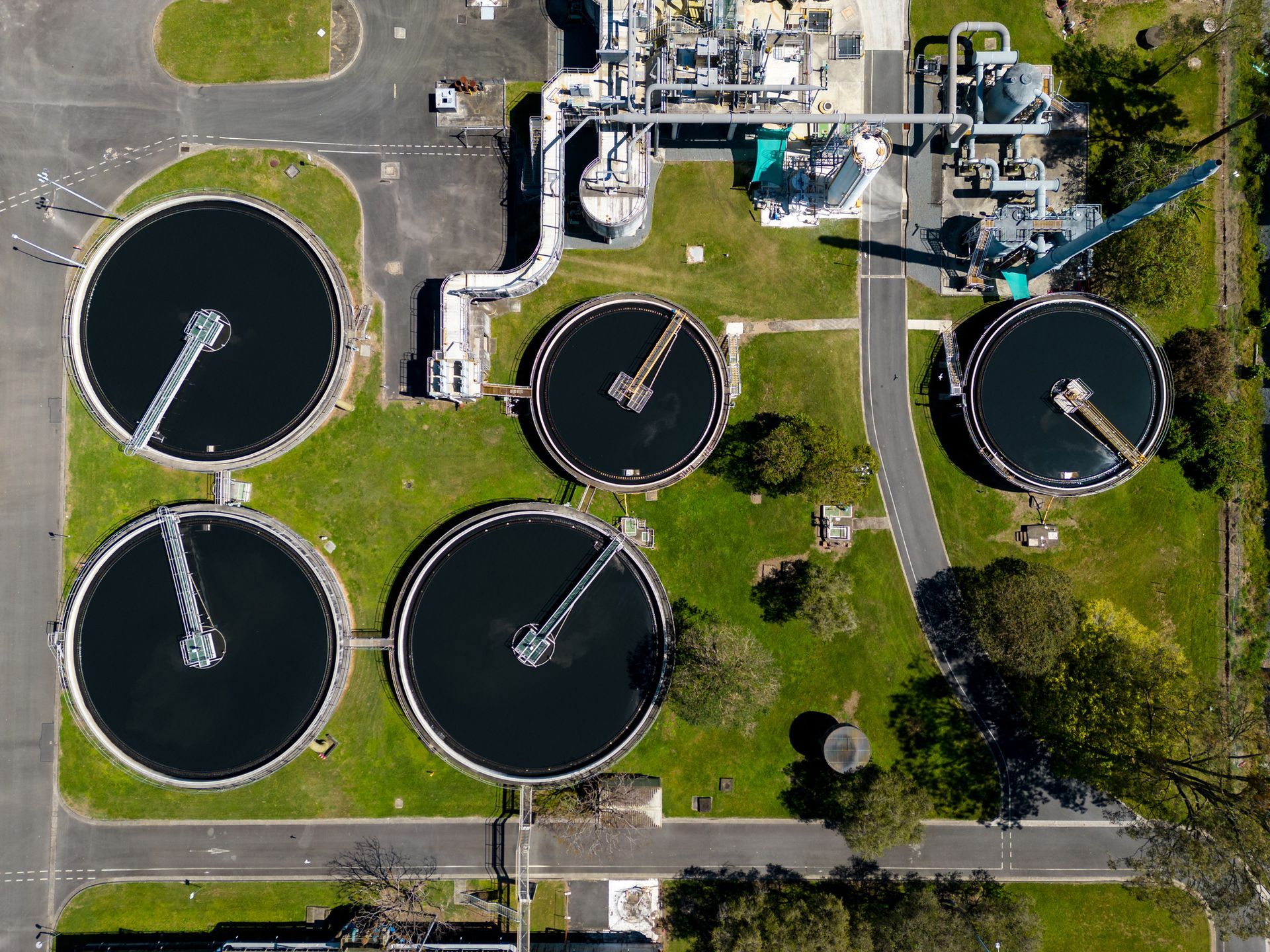 An aerial view of a sewage treatment plant surrounded by grass and trees.