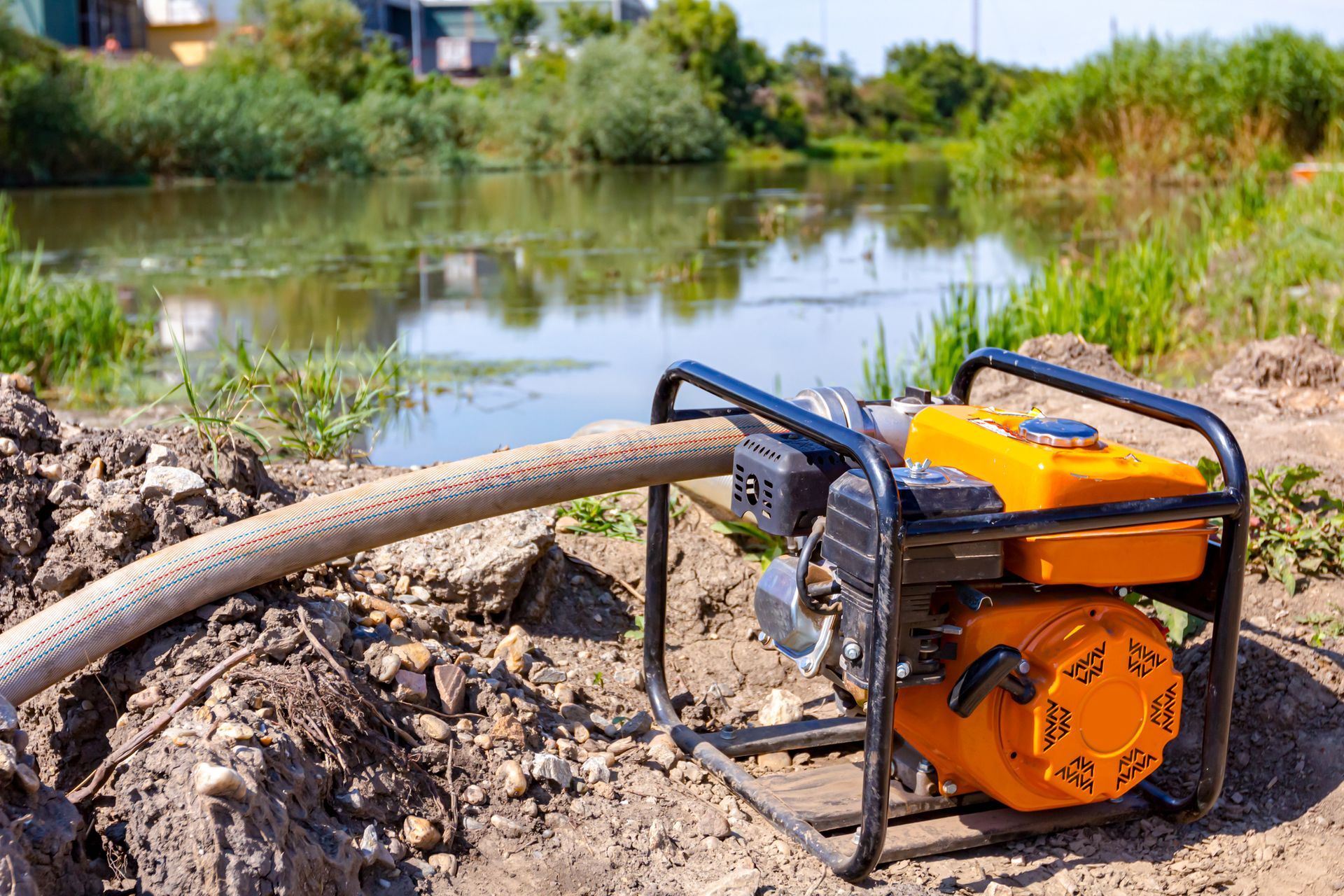 A water pump is sitting on the ground next to a river.