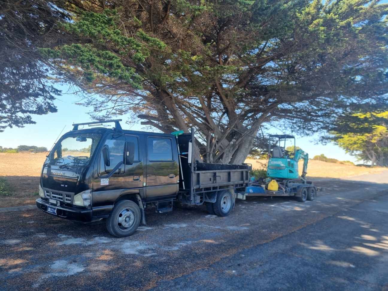 A man is kneeling in a kitchen next to a bucket of water.