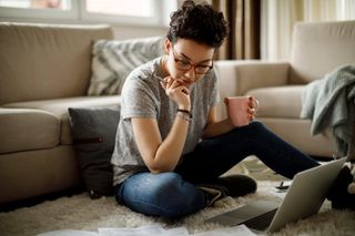 Woman working on laptop on living room floor | Kolsky Realty and Management Co