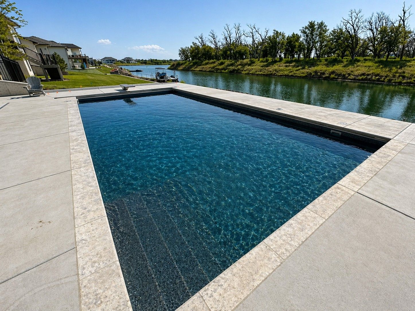 Rectangular outdoor pool beside a calm canal under a clear blue sky