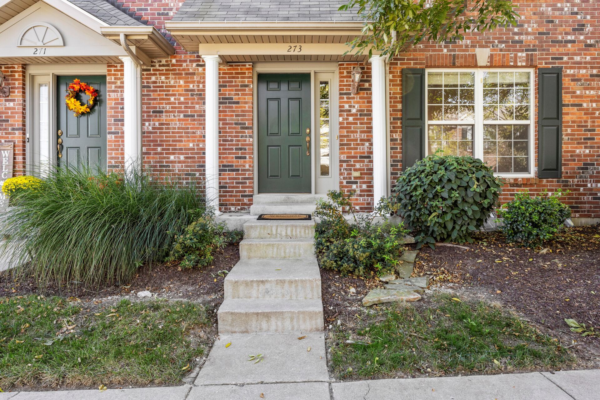 A brick house with a green door and a wreath on the front door.