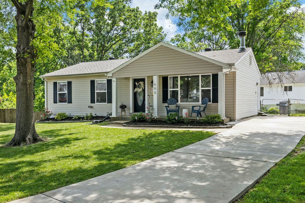 A white house with a driveway leading to it is for sale.