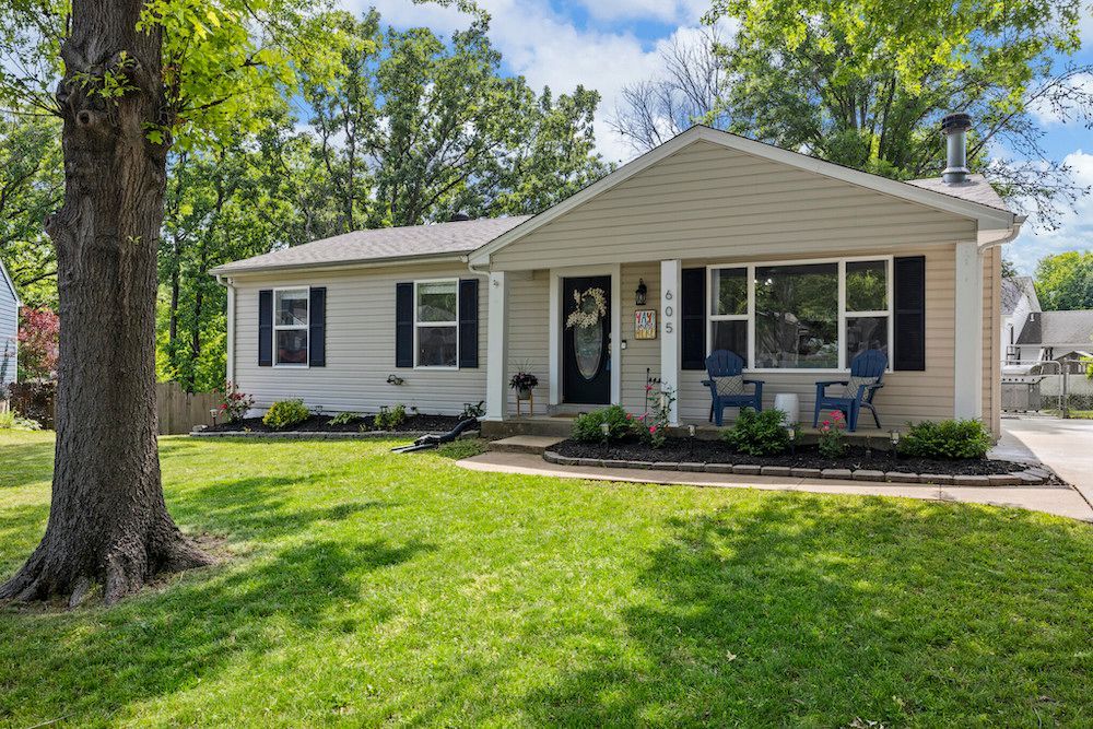 A house with a large lawn and a tree in front of it.