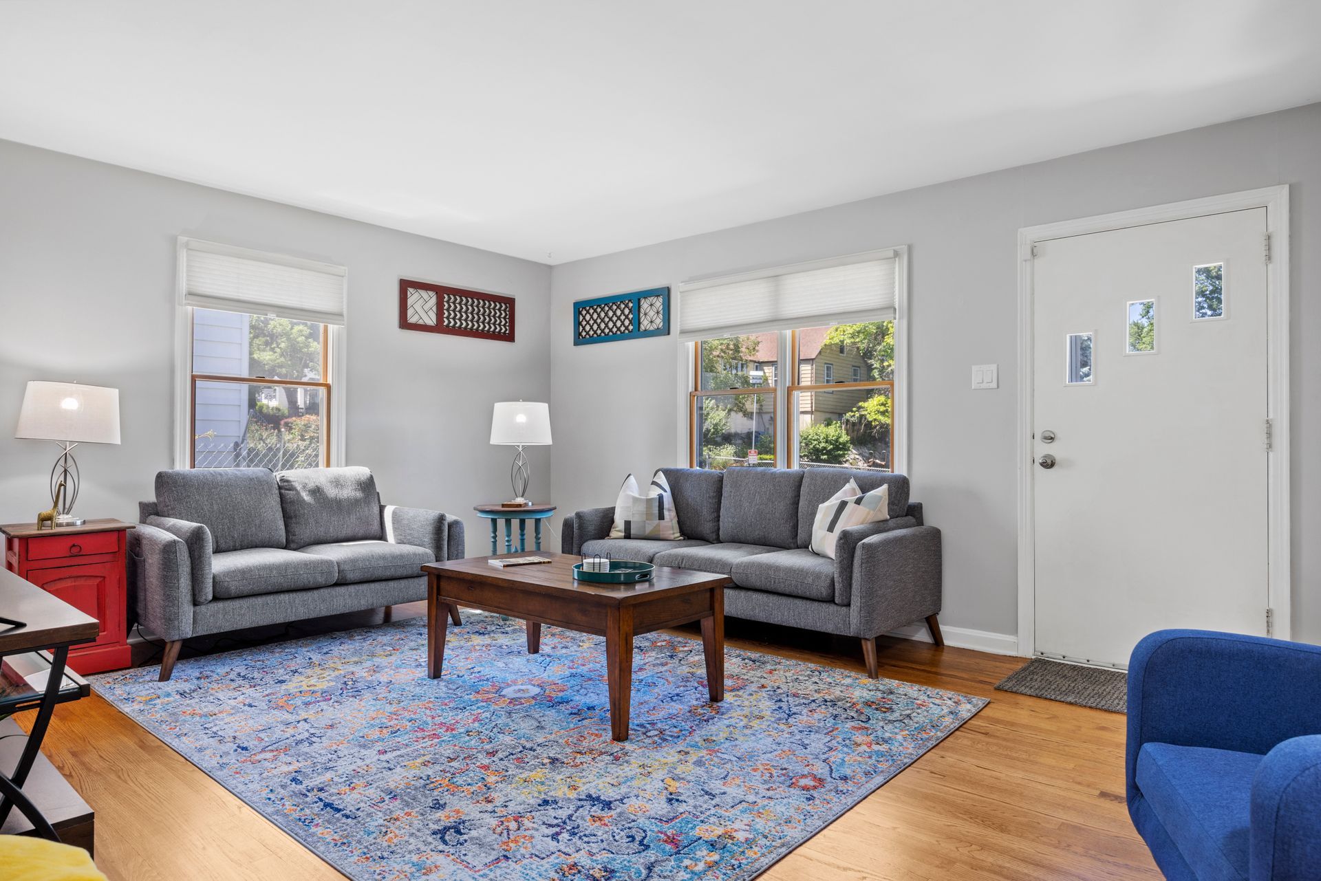A living room with two couches , a coffee table , and a blue chair.