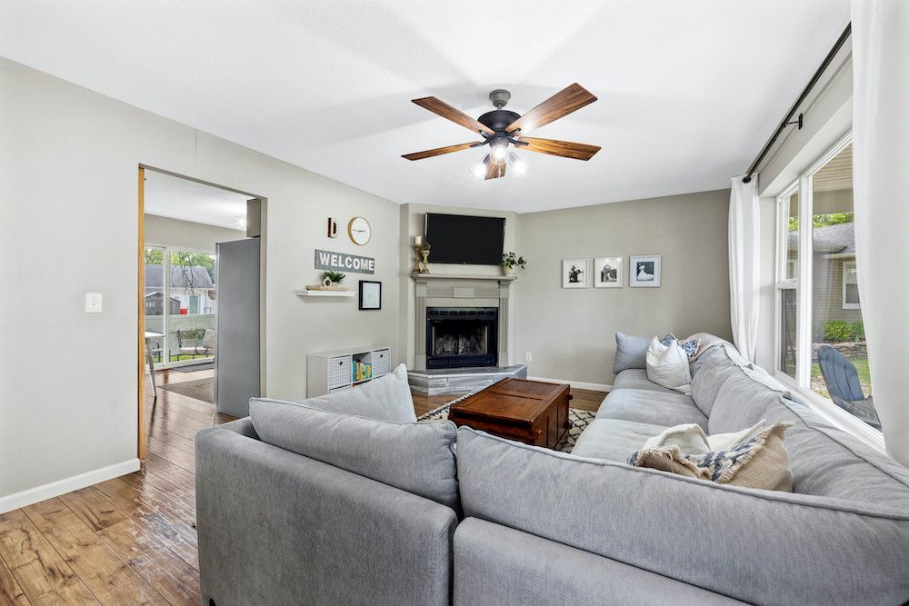 A living room with a couch , fireplace and ceiling fan.