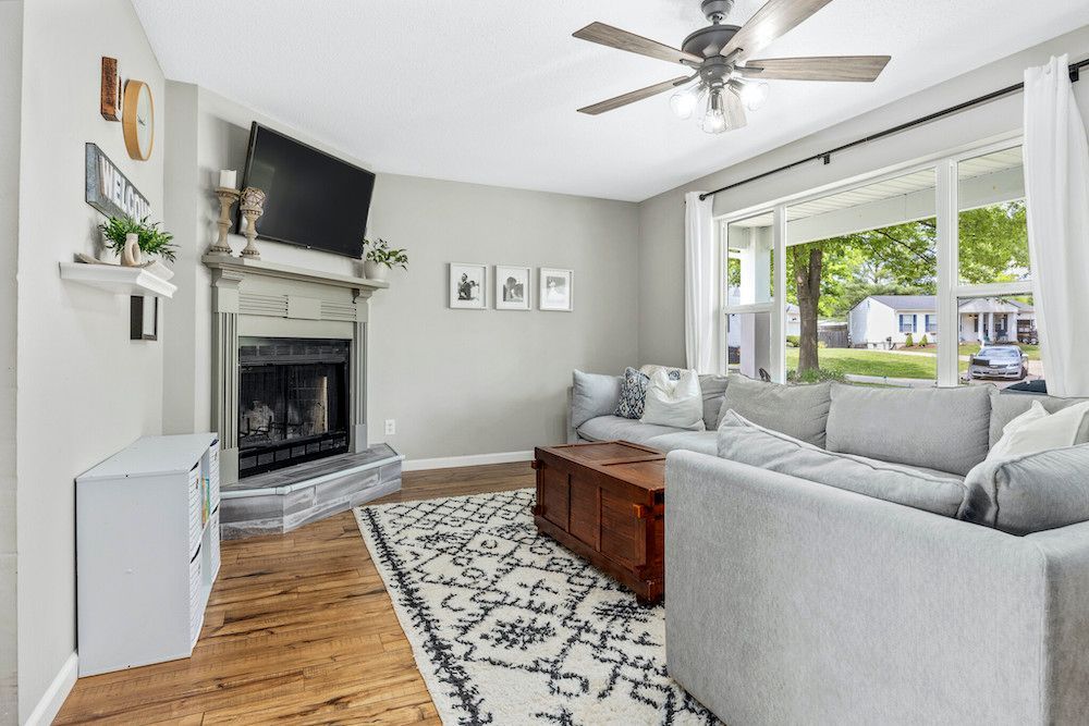 A living room with a couch , fireplace , television and ceiling fan.