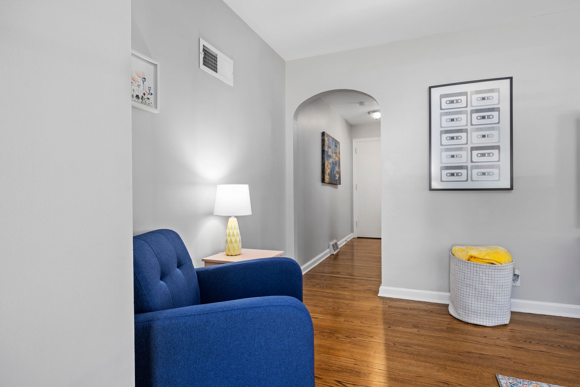 A living room with a blue chair , lamp , and ottoman.
