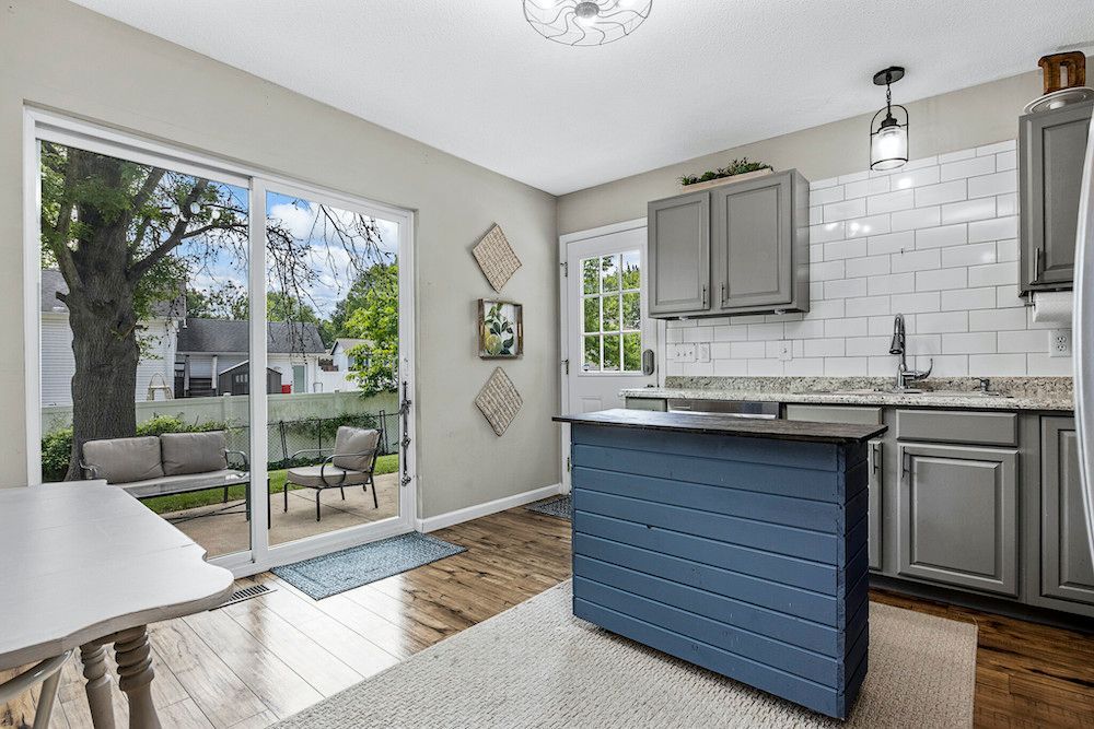A kitchen with a blue island and sliding glass doors leading to a patio.