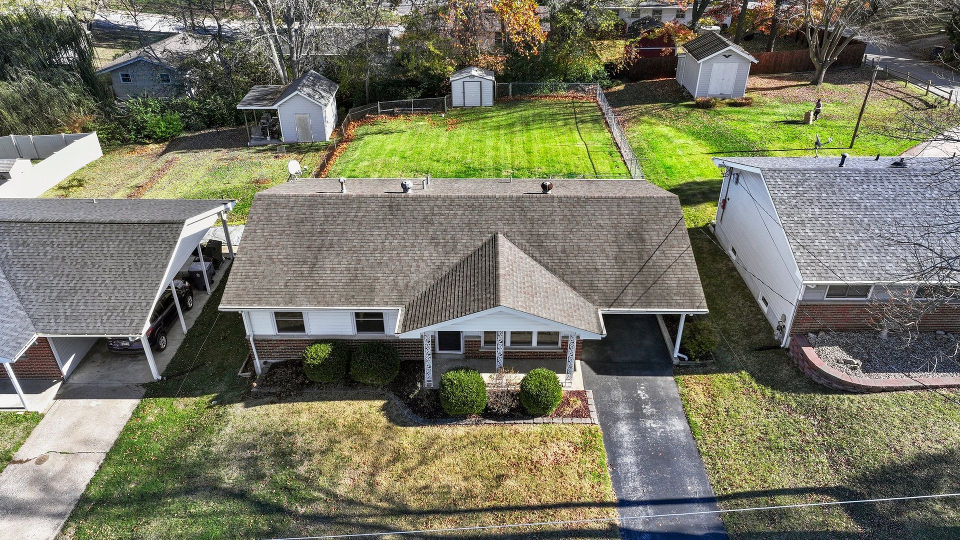 An aerial view of a house with a gray roof in a residential area.