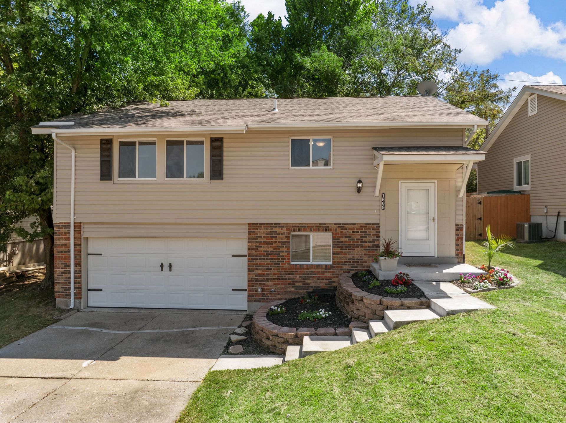 A large white house with two garages and a lush green yard.