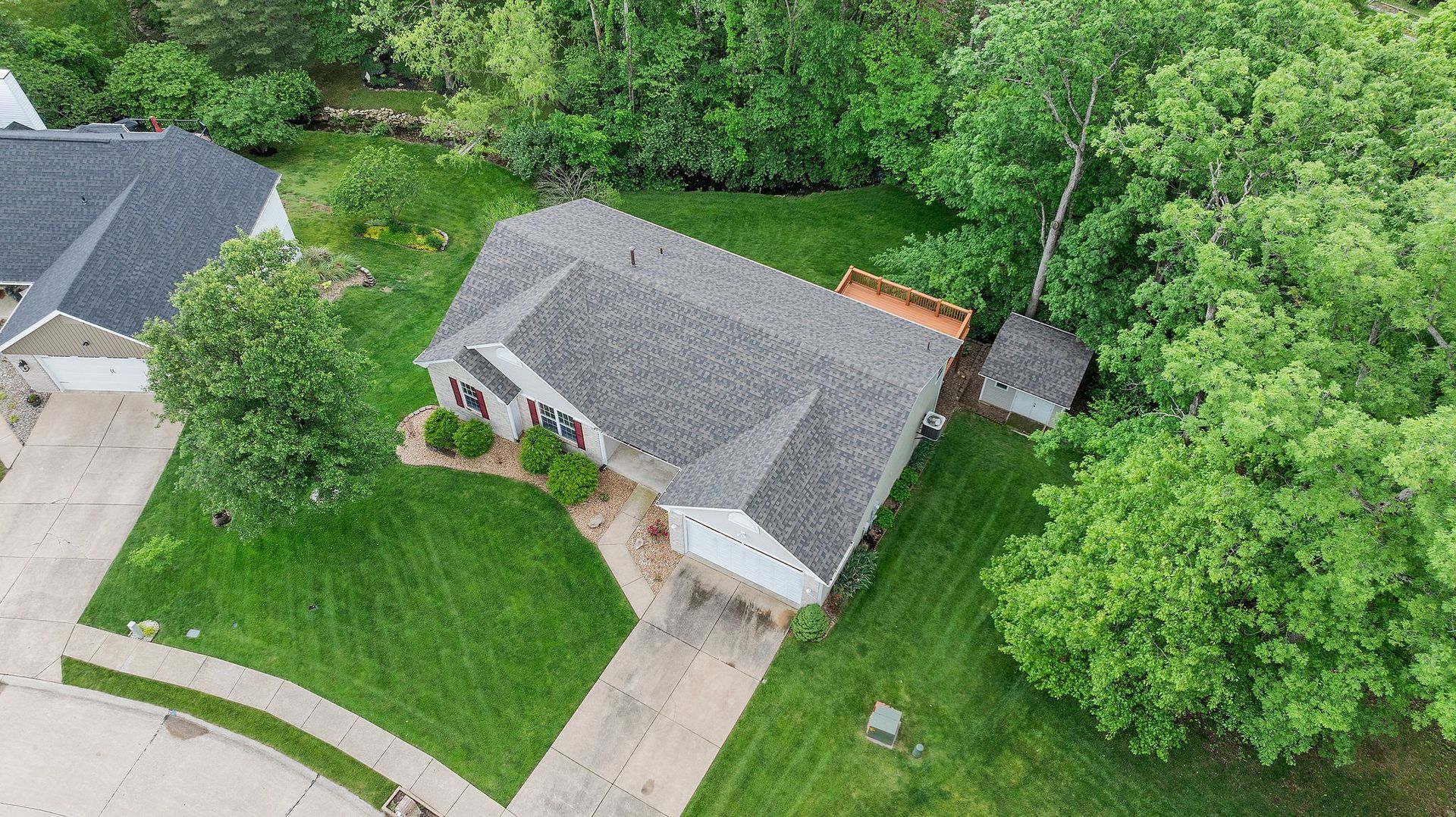 An aerial view of a house surrounded by trees and grass.