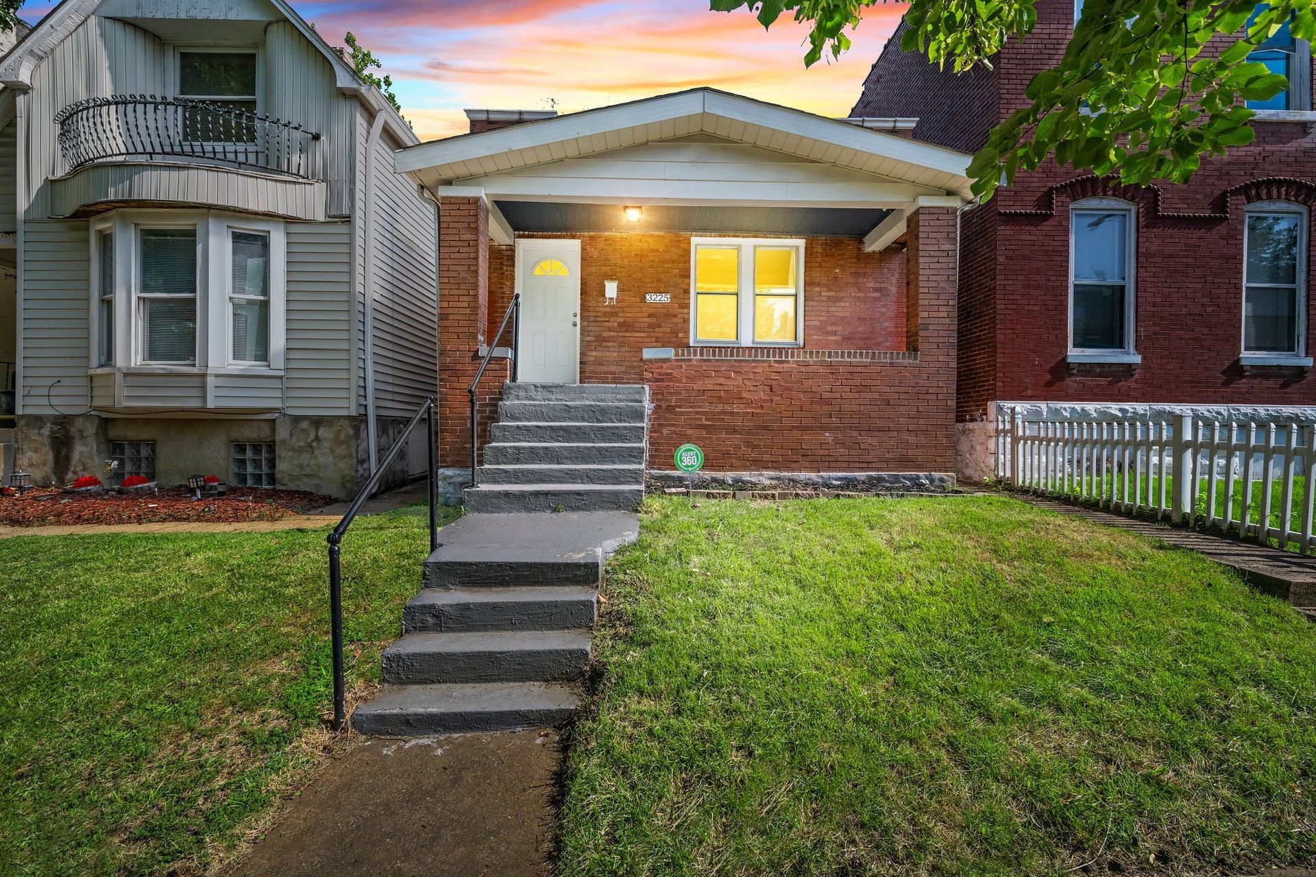 A large brick house with two garages and a lush green lawn