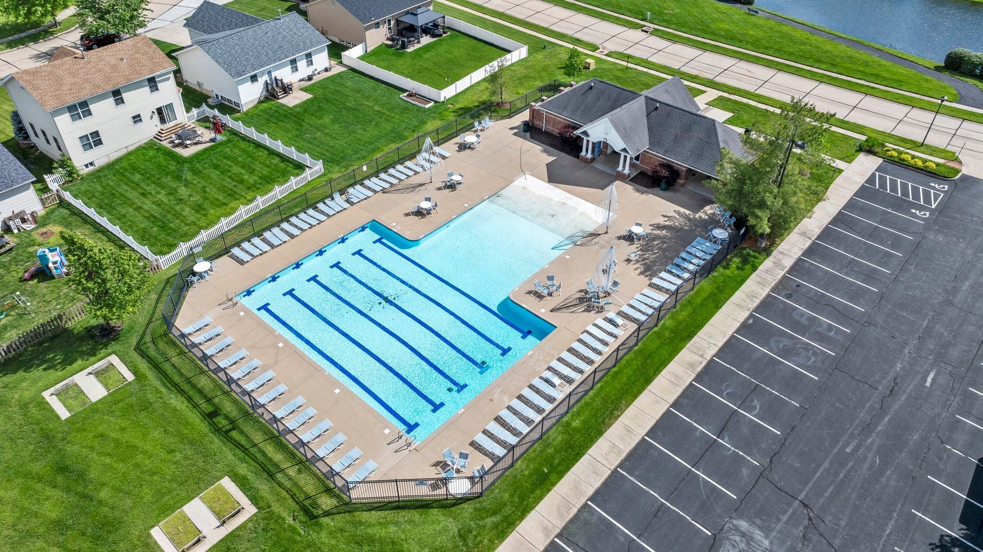 An aerial view of a large swimming pool surrounded by houses and a parking lot.