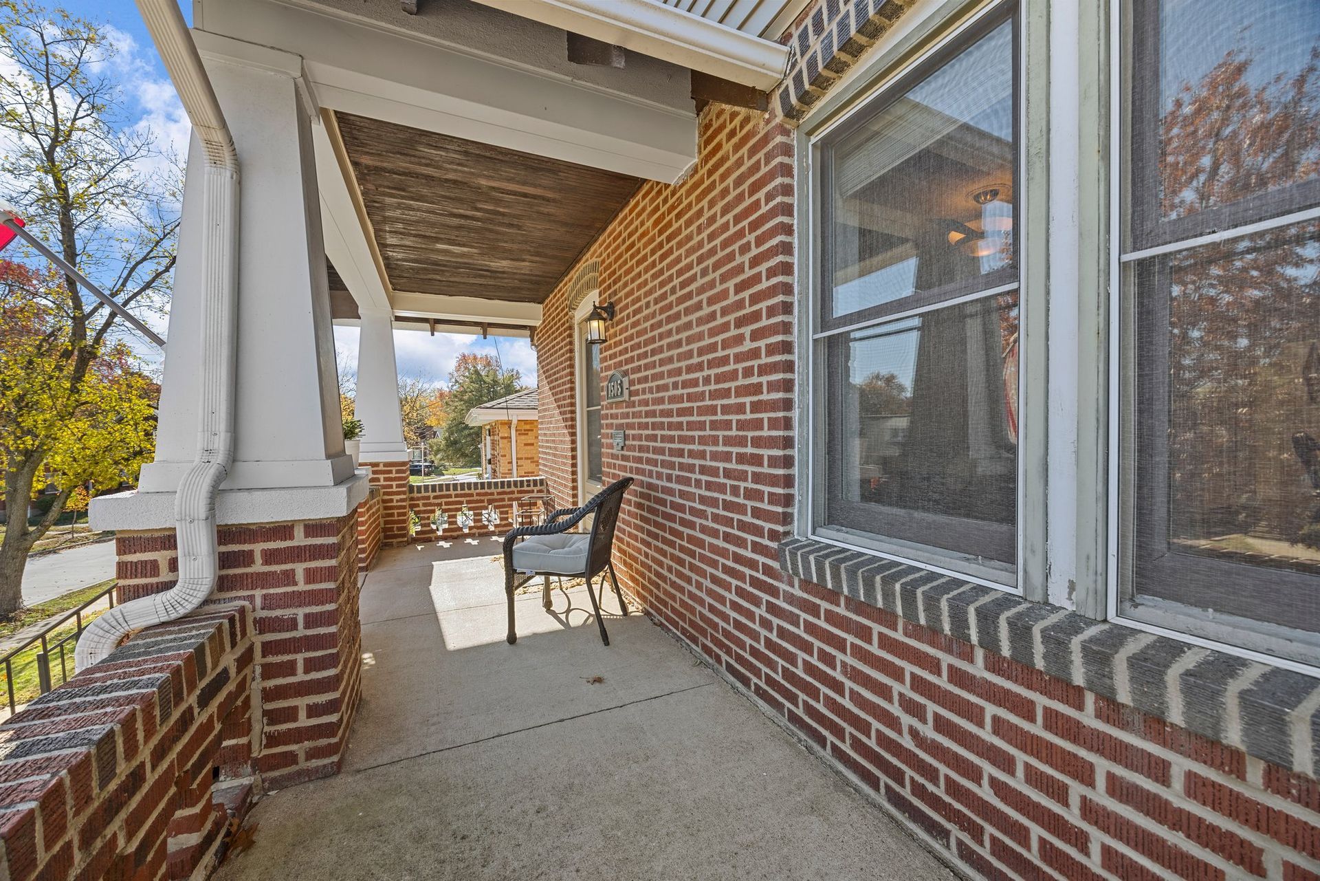 A brick house with a porch and a chair on it.