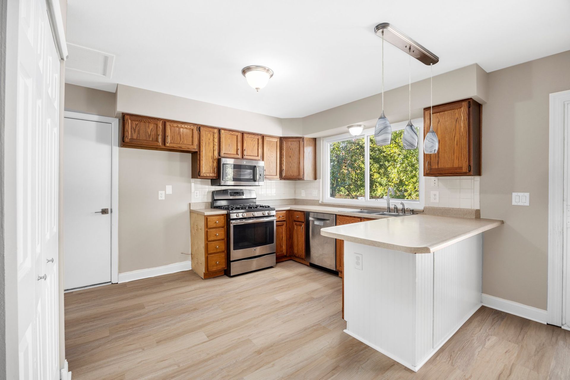 A kitchen with wooden cabinets , stainless steel appliances , and a large island.