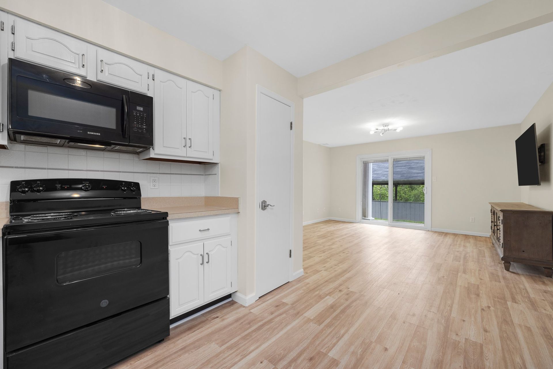 A kitchen with a black stove , microwave , and television.